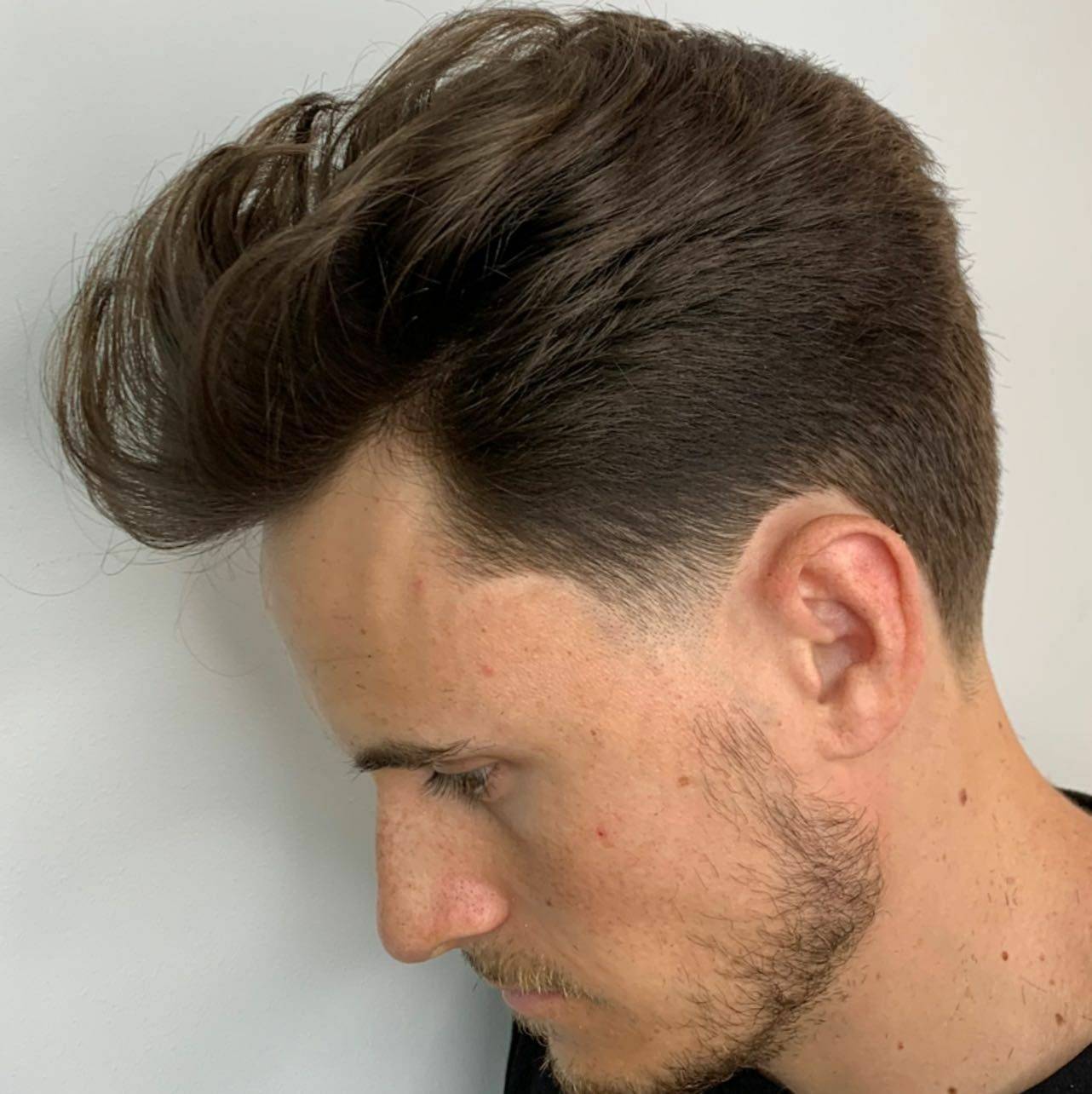 Tupé clásico con volumen peinado hacia atrás, vista de perfil